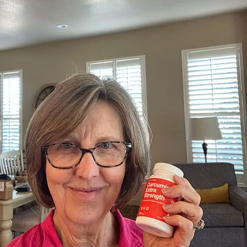 woman standing in her living room while holding Better Way Health's Curcumin Extra Strength